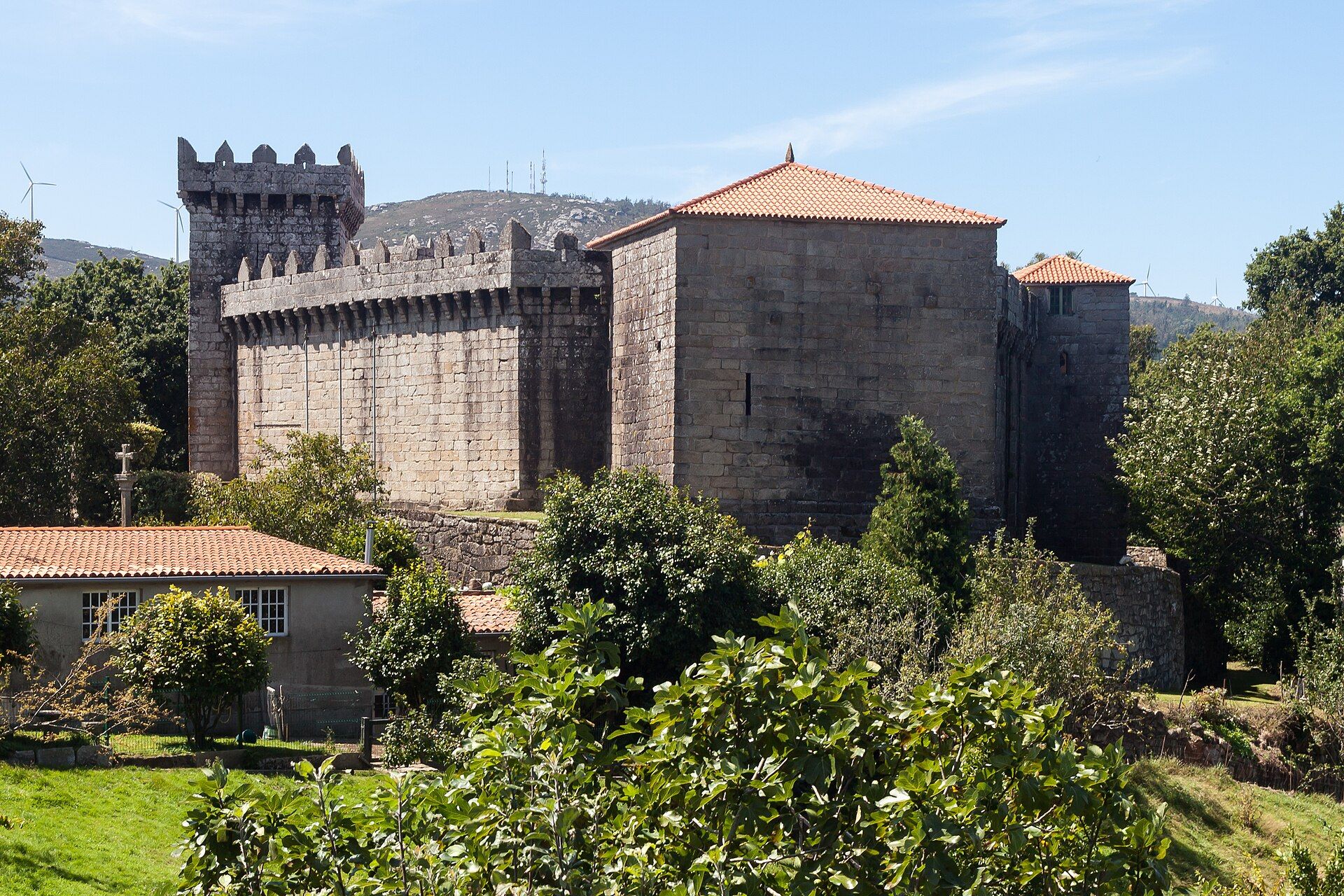 O Castelo de Vimianzo desde o sur: muralla ameada sobre ménsulas, torre da homenaxe e o corpo da vivenda con tellado de tella vermella.