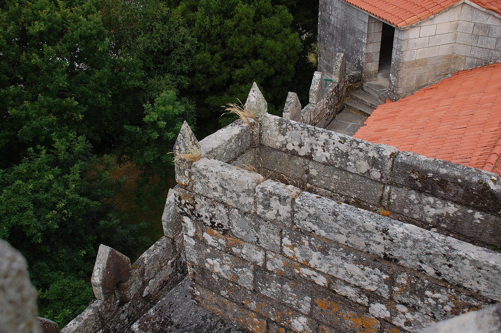 Paseo de rolda do Castelo de Vimianzo visto desde arriba, coas ameas e o tellado de tella ao fondo.