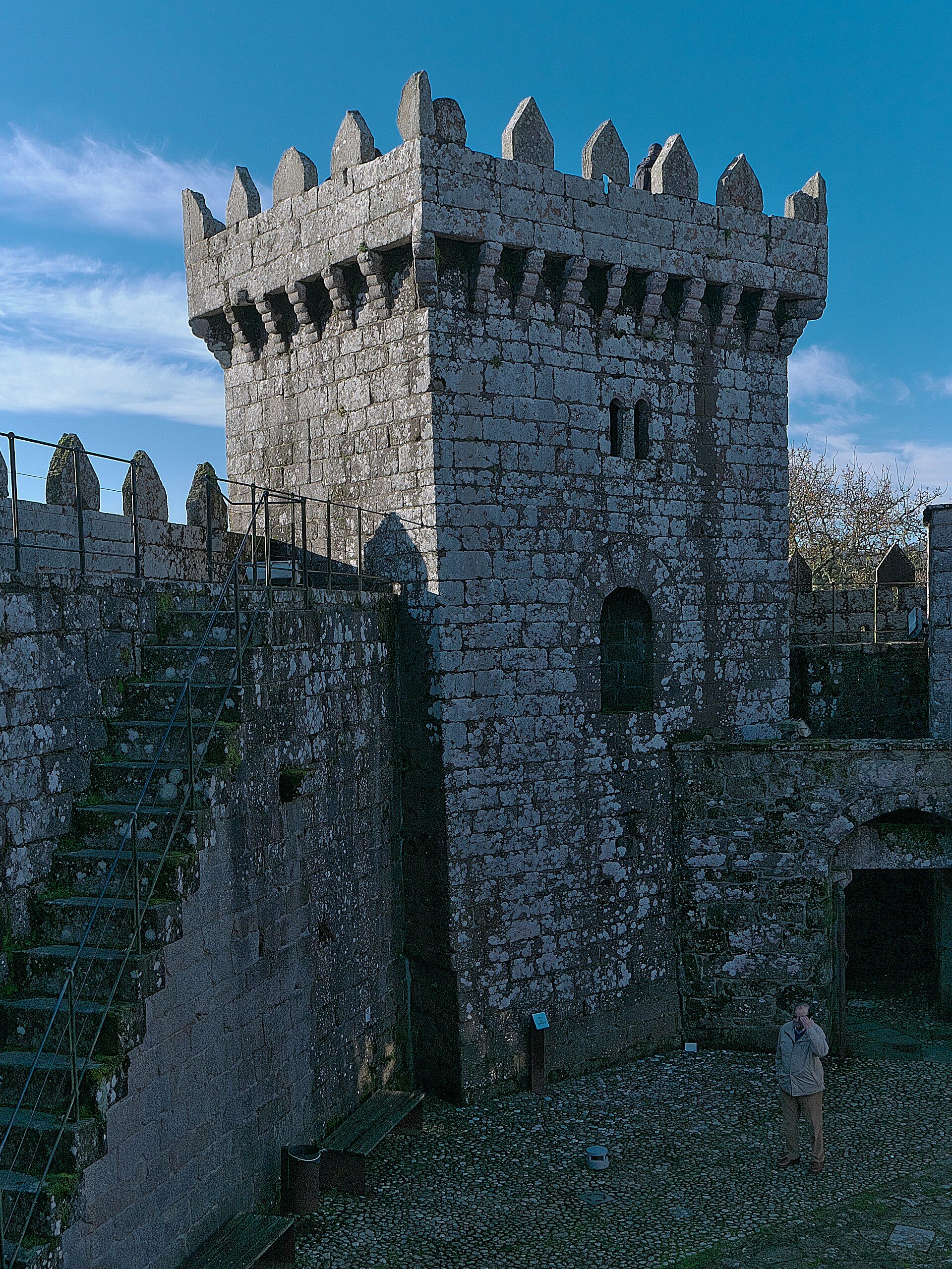 Torre da homenaxe do Castelo de Vimianzo en vertical, coas ameas recortadas contra o ceo.